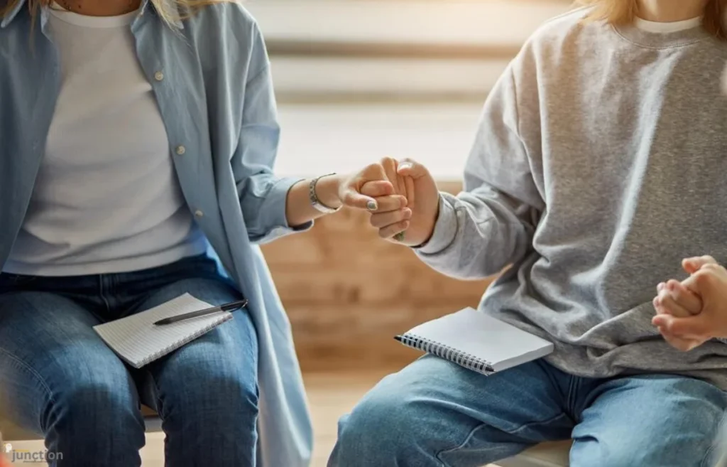 Two people holding hands in a therapy session, symbolizing support and recovery at Acadia Healthcare.