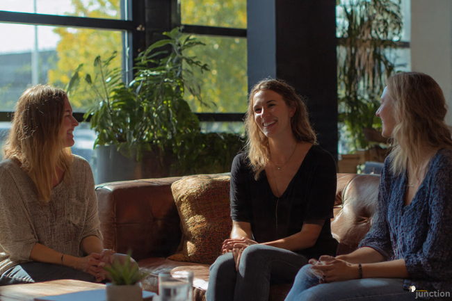 A group of friends sitting together, talking and smiling in a cozy setting, offering emotional Support through conversation and connection.