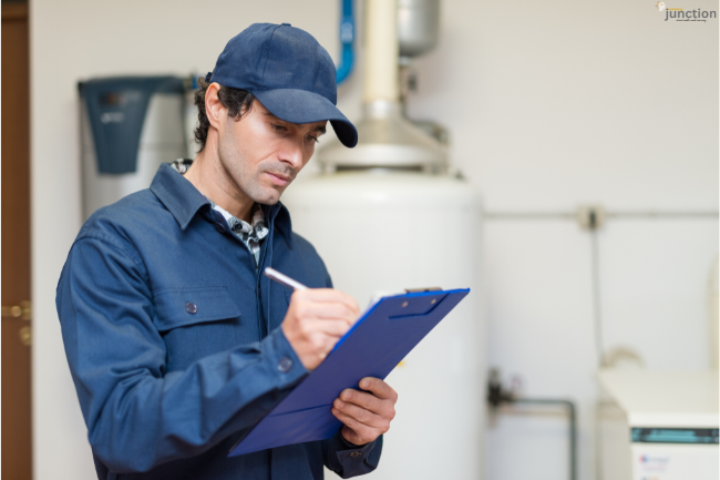 Technician inspecting a Water Heater and filling out a compliance checklist on a clipboard inside a utility room.
