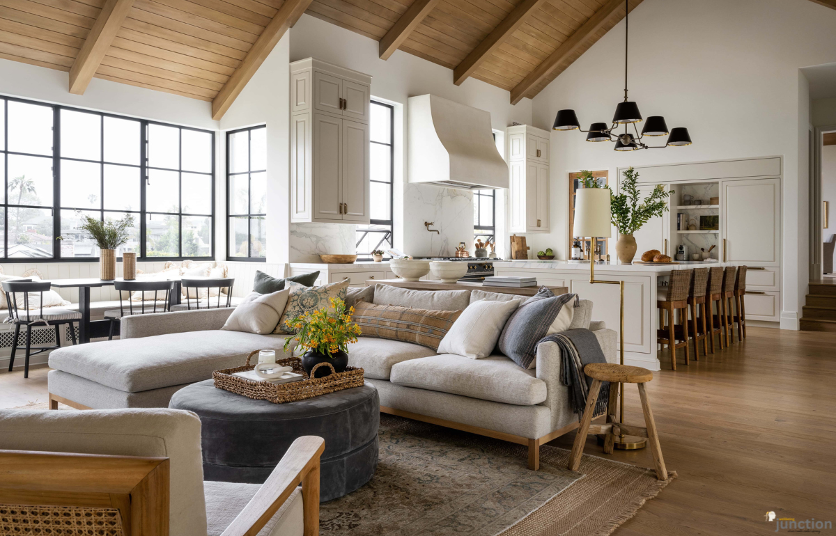 Open-plan living room and kitchen showcasing layered Wood Tones—oak floors, beamed ceiling, neutral sofas, and mixed wood furniture.