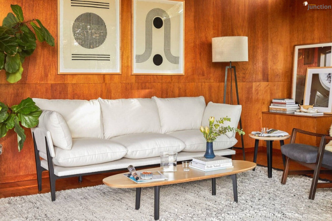 Modern living room with rich Wood Tones, featuring a white sofa, mid-century furniture, abstract wall art, and a cozy rug.
