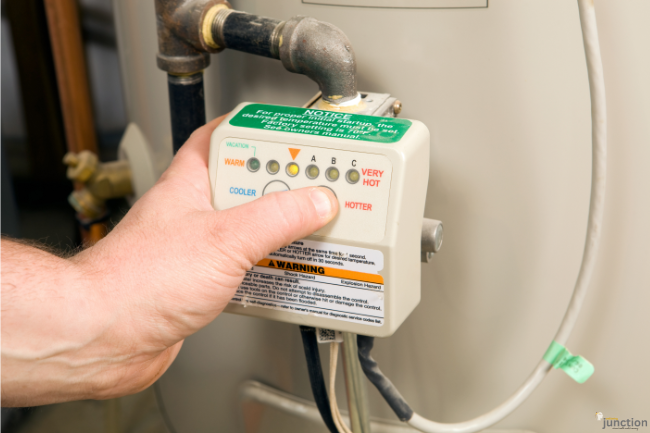 Hand adjusting temperature control on a Water Heater thermostat to improve energy efficiency.